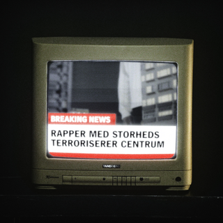Et gammeldags fjernsyn viser en nyhedsudsendelse med en “BREAKING NEWS” banner. Teksten på skærmen lyder: “Rapper med storheds terroriserer centrum”, og baggrunden viser en sort-hvid byscene med bygninger og en person i billedet. Stemningen er dramatisk og satirisk.